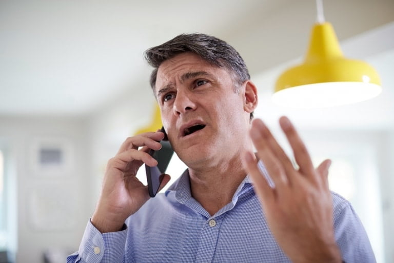 Zirytowany mężczyzna rozmawia przez telefon komórkowy — ilustracja do artykułu o wycofaniu zgody na telemarketing